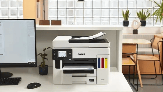 Canon PIXMA TR150 wireless printer on a desk, next to a computer.